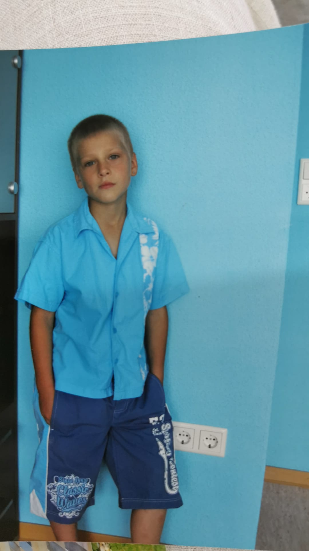 Edik als Kind vor einer blauen Wand